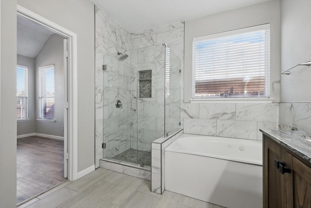 bathroom with a garden tub, vaulted ceiling, a shower stall, vanity, and baseboards