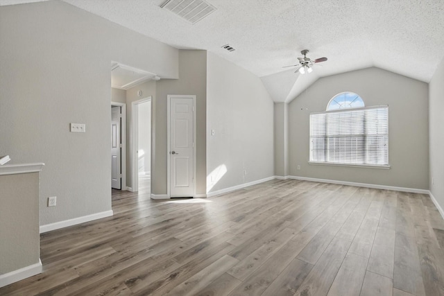 unfurnished living room with visible vents, vaulted ceiling, a textured ceiling, and wood finished floors