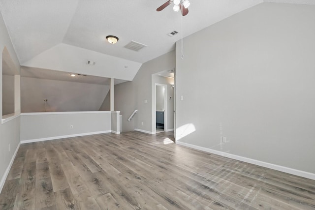 unfurnished living room with baseboards, visible vents, vaulted ceiling, and wood finished floors