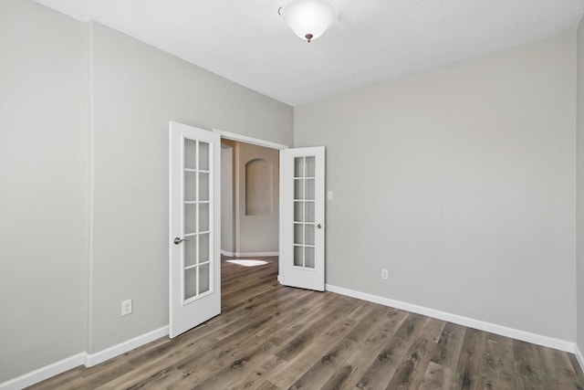 unfurnished room featuring french doors, baseboards, and wood finished floors