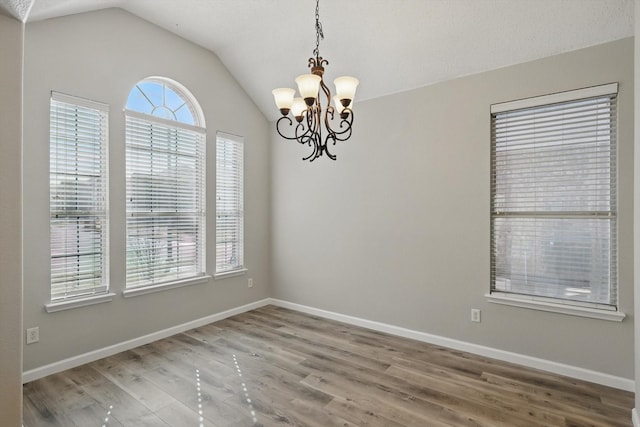 empty room featuring lofted ceiling, baseboards, and wood finished floors