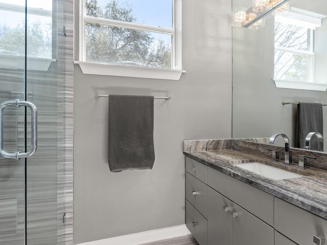 full bath with a stall shower, plenty of natural light, baseboards, and vanity