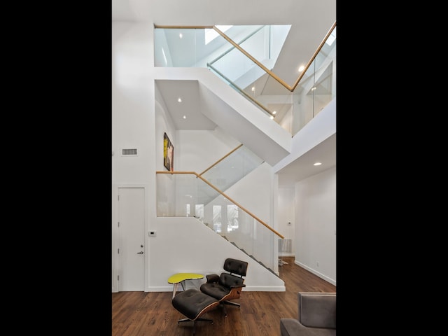 entryway with visible vents, stairway, a towering ceiling, and wood finished floors