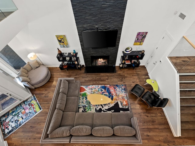 living area with a fireplace, visible vents, stairway, wood finished floors, and baseboards