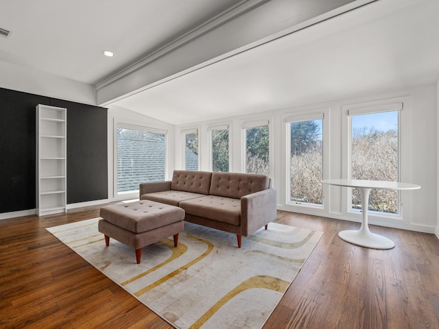 living area featuring lofted ceiling with beams, wood finished floors, visible vents, and baseboards