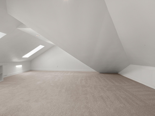 bonus room with lofted ceiling with skylight and light colored carpet