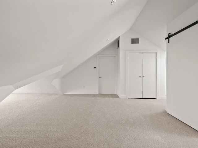 bonus room featuring vaulted ceiling, carpet floors, a barn door, and visible vents