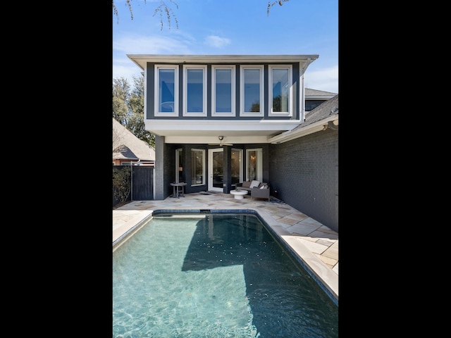 rear view of house with a fenced in pool, a patio area, brick siding, and fence