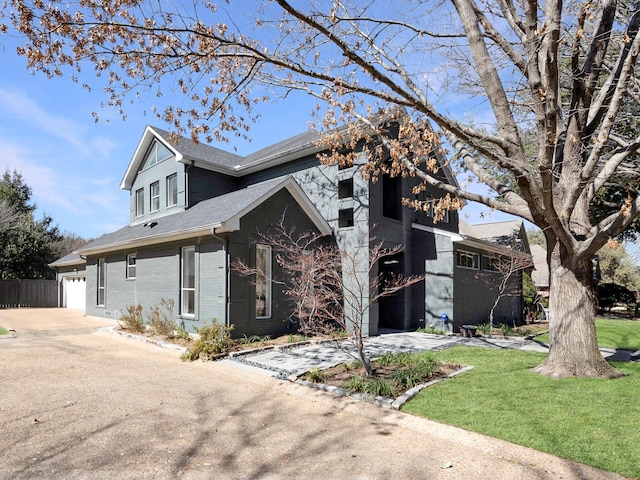 view of front facade with concrete driveway, brick siding, a front lawn, and roof with shingles