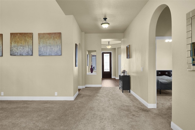 entrance foyer with arched walkways, carpet flooring, and baseboards