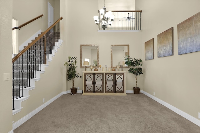 carpeted entryway featuring a chandelier, a high ceiling, stairs, and baseboards