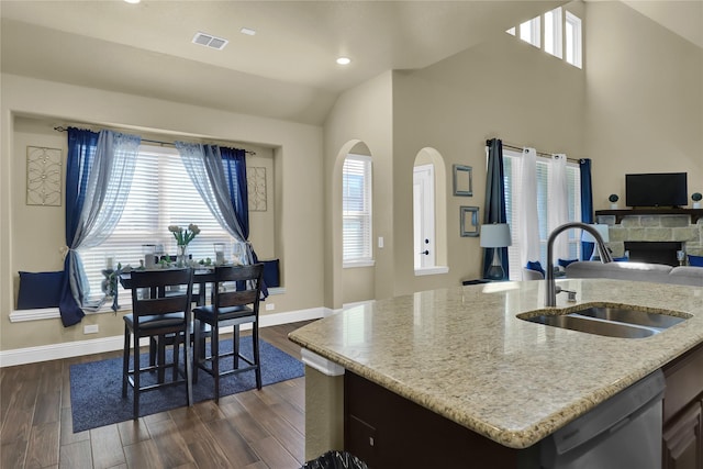 kitchen with lofted ceiling, visible vents, open floor plan, a sink, and dishwasher