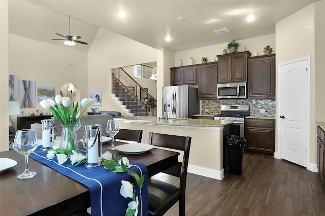 kitchen featuring dark brown cabinetry, dark wood-type flooring, visible vents, open floor plan, and appliances with stainless steel finishes