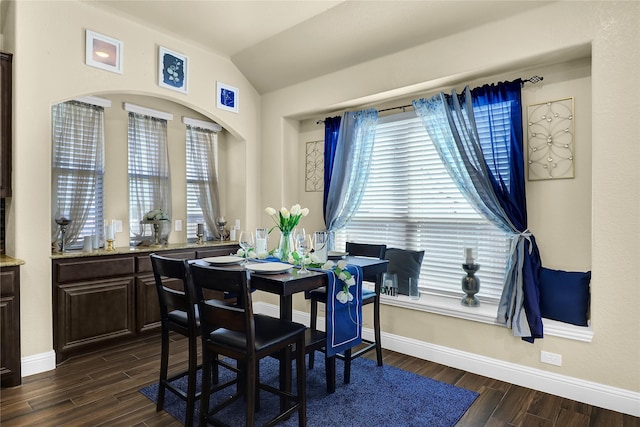 dining room featuring dark wood-style floors, lofted ceiling, and baseboards