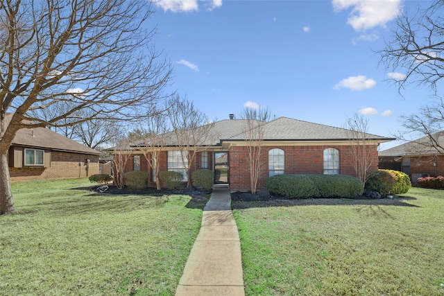 ranch-style house featuring brick siding, a front lawn, and a shingled roof