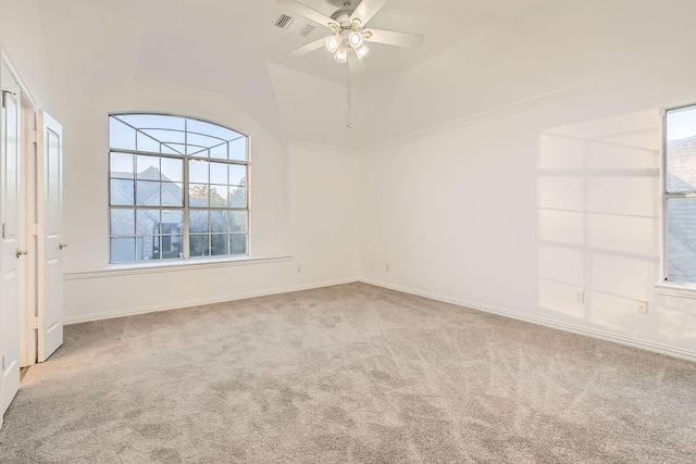 carpeted empty room featuring lofted ceiling, baseboards, visible vents, and a ceiling fan