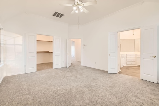 unfurnished bedroom with light carpet, visible vents, connected bathroom, ornamental molding, and a spacious closet