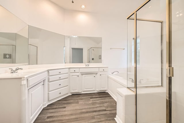 full bath with a sink, wood finished floors, a bath, double vanity, and a stall shower