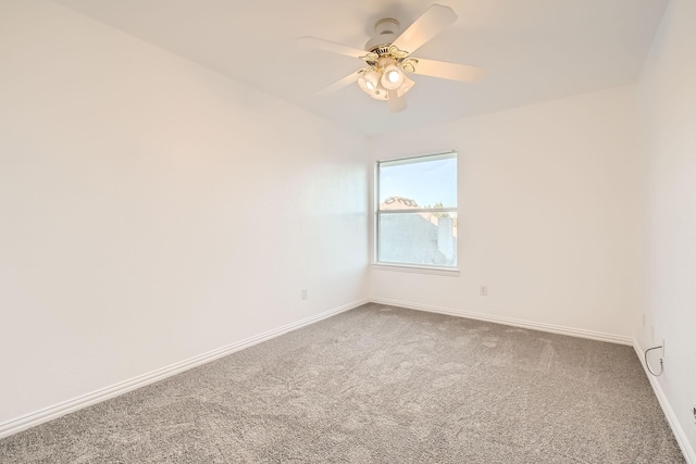 carpeted spare room featuring a ceiling fan and baseboards