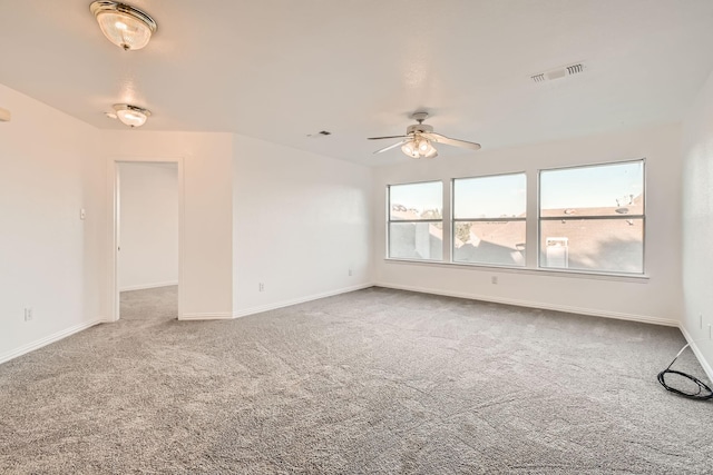 carpeted spare room with baseboards, visible vents, and a ceiling fan