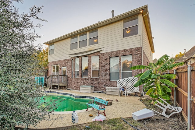 rear view of property featuring fence private yard, a fenced in pool, a patio, and brick siding