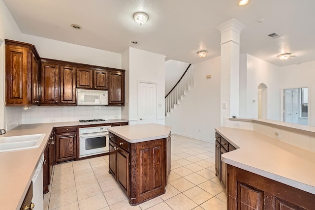 kitchen featuring white appliances, tasteful backsplash, light tile patterned floors, light countertops, and a sink