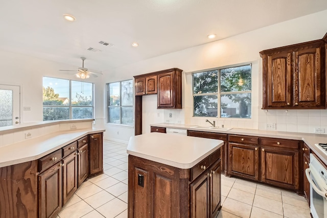 kitchen featuring visible vents, backsplash, a kitchen island, a sink, and oven