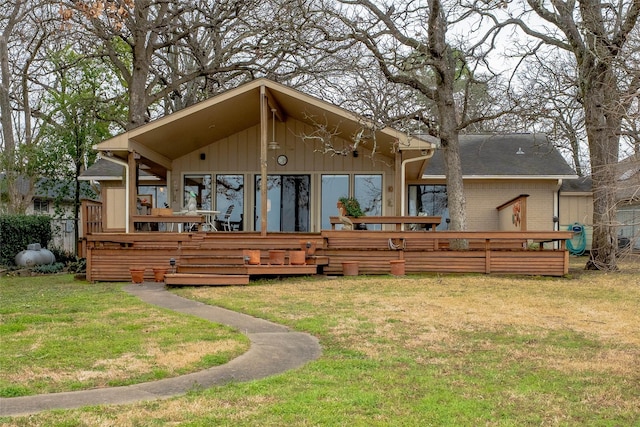 rear view of house with a deck, a yard, and brick siding