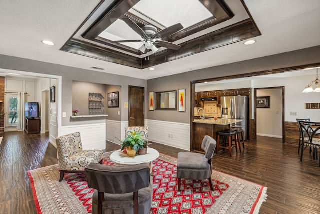 living area featuring recessed lighting, a ceiling fan, wainscoting, dark wood-style floors, and a tray ceiling