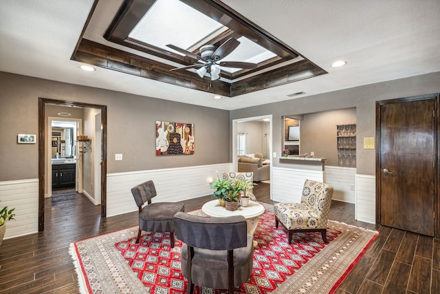 sitting room featuring a raised ceiling, wainscoting, and dark wood finished floors