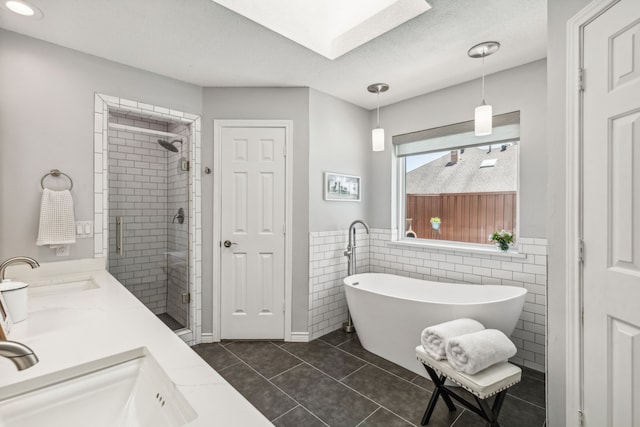 bathroom with a freestanding tub, a sink, a shower stall, and tile patterned floors