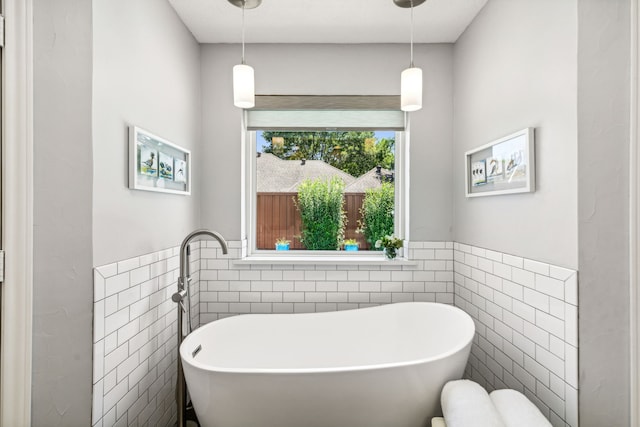 full bathroom featuring a freestanding tub, tile walls, and a wainscoted wall