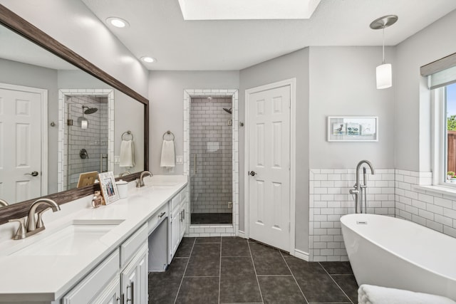 full bath featuring a freestanding tub, a stall shower, tile patterned flooring, and a sink