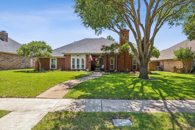 view of front facade featuring a front yard, a chimney, and brick siding