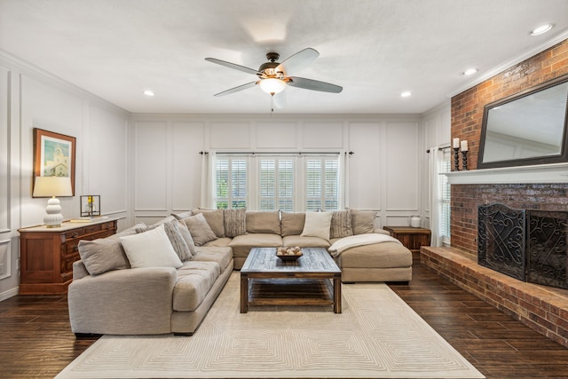 living room featuring ceiling fan, a decorative wall, dark wood-style flooring, a fireplace, and ornamental molding