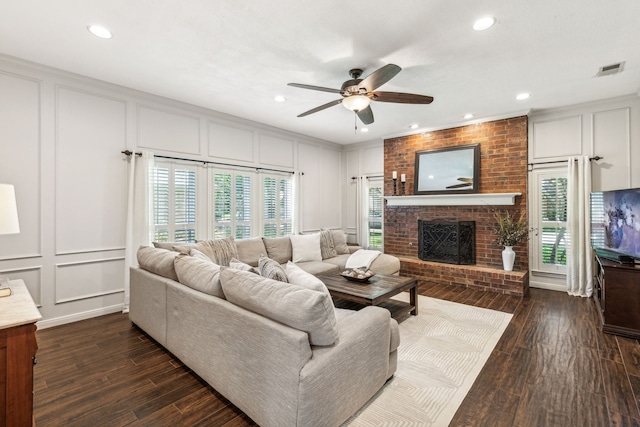 living room with a healthy amount of sunlight, dark wood-style flooring, a fireplace, and a decorative wall