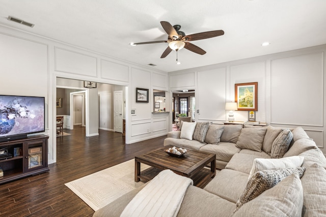 living area featuring a ceiling fan, dark wood finished floors, visible vents, and a decorative wall