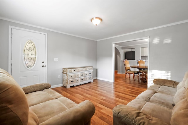 living area featuring baseboards, wood finished floors, and crown molding