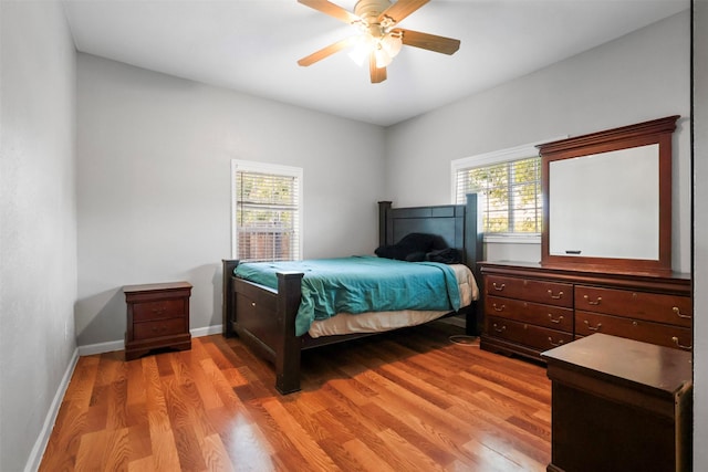 bedroom with baseboards, a ceiling fan, and light wood-style floors