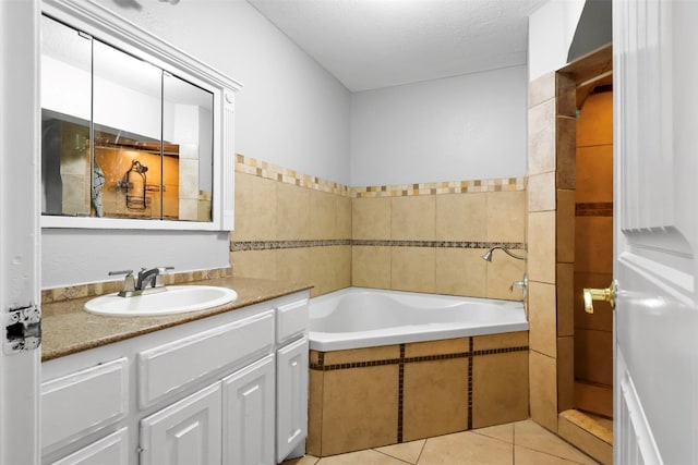 bathroom with a garden tub, tile patterned flooring, a textured ceiling, and vanity