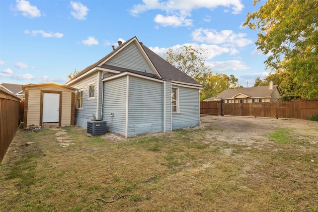 rear view of house featuring a fenced backyard, a yard, a shed, an outdoor structure, and central AC