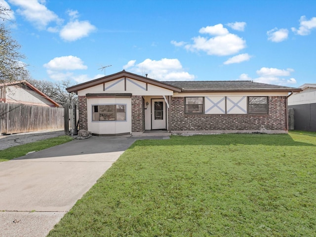 view of front facade featuring brick siding, a front yard, and fence