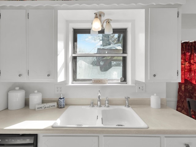 kitchen featuring black dishwasher, light countertops, a sink, and white cabinets