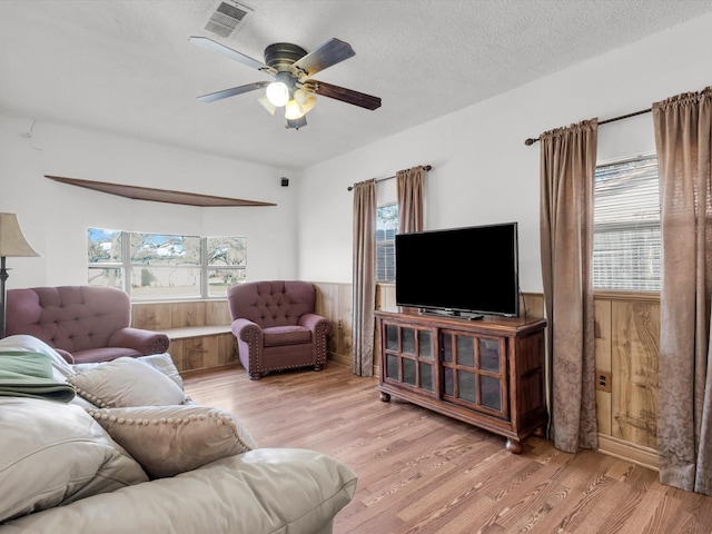 living area featuring wainscoting, wood finished floors, and a healthy amount of sunlight