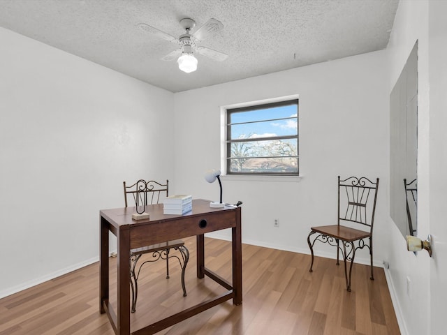 office area with light wood-style floors, ceiling fan, a textured ceiling, and baseboards