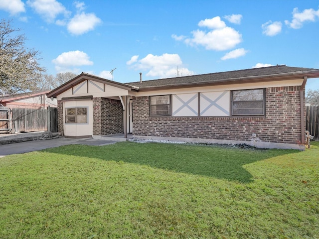 back of house featuring brick siding, fence, and a lawn