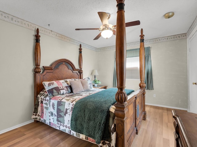 bedroom featuring light wood finished floors, a ceiling fan, baseboards, and a textured ceiling