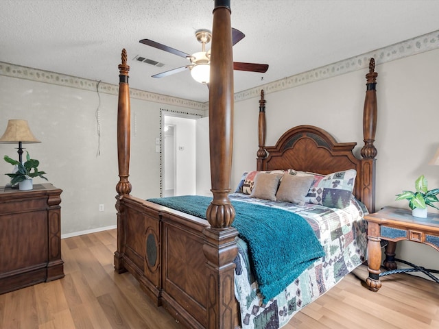 bedroom featuring visible vents, ceiling fan, a textured ceiling, and wood finished floors