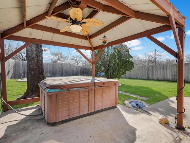 view of patio / terrace with a hot tub, a fenced backyard, a ceiling fan, and a gazebo