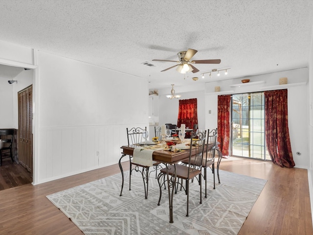 dining room with ceiling fan, a textured ceiling, visible vents, and wood finished floors